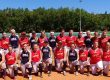 A group photo of softball players in red and blue uniforms on a field.